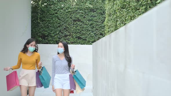 Asian woman wearing face mask. Happy woman with shopping bags enjoying