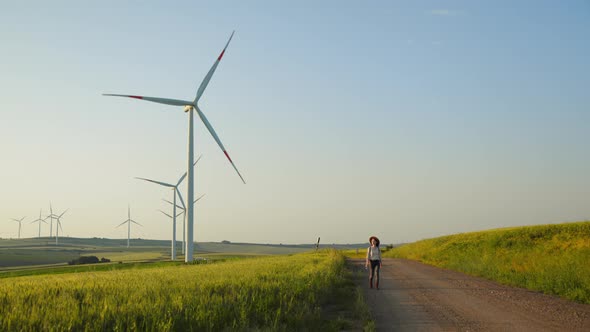 Young woman with a retro camera with wind mill turbines ecology green