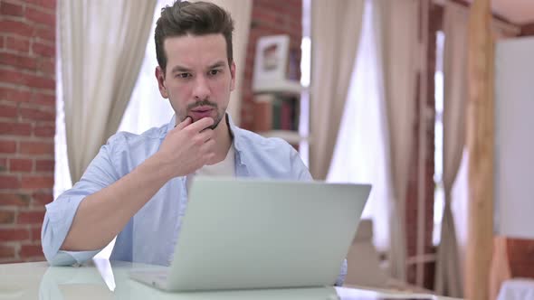 Young Man Thinking and Working on Laptop