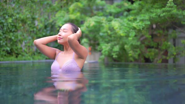 Young asian woman enjoy around outdoor swimming pool for leisure