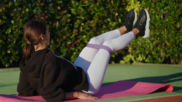 Sporty Lady During Her Fitness Workout with Rubber Resistance Band Outdoors