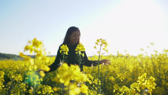 Asian woman running on track and touching flower in yellow field