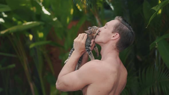 Brutal and Strong Caucasian Man Plays with Nice Little Kitten