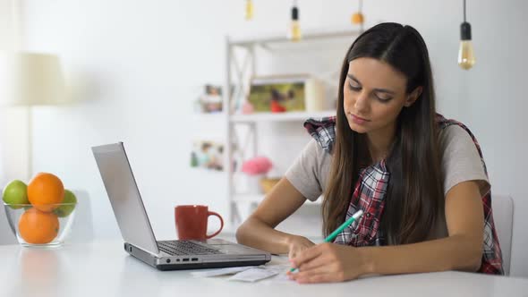 Young Woman With Laptop and Bills Counting Incomes and Expenses, Home Budget