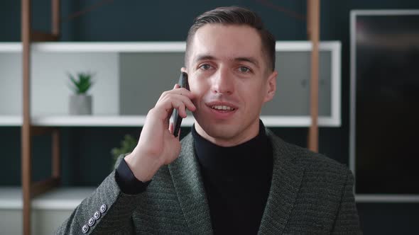 Portrait of Confident Businessman Talking on Mobile Phone in Modern Office