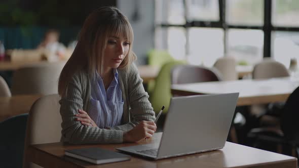 An Asian Woman Sits Brooding and Looks at a Laptop Screen