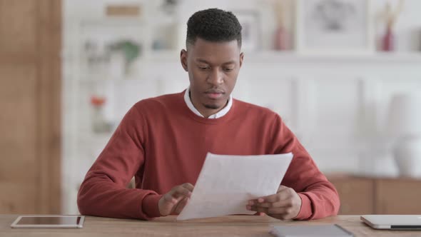 African Man Reading Reports while Sitting in Office