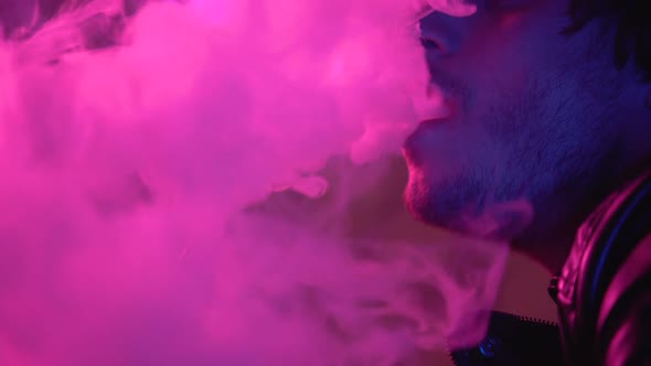 Man Vaping E-Cigarette in Darkness, Exhaling Clouds of Smoke, Unhealthy Habit