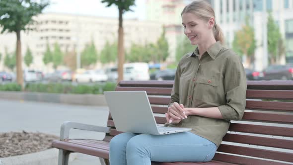 Woman Talking on Video Call while Sitting Outdoor on Bench