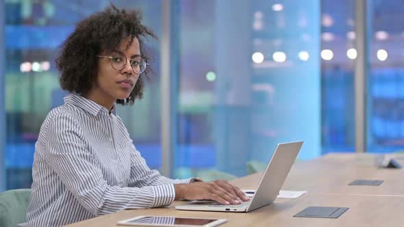 African Businesswoman with Laptop Looking at Camera in Office