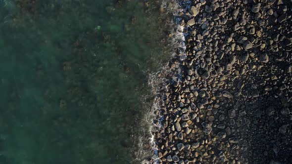 A high revealing drone video looking down at the raw rocky coastline of the small town of Bargara lo