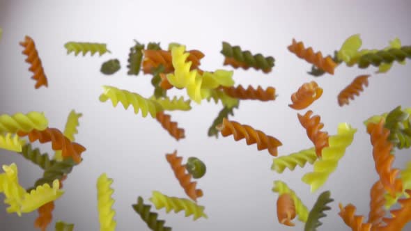 Colored Pasta Fusili Flying Up on a White Background