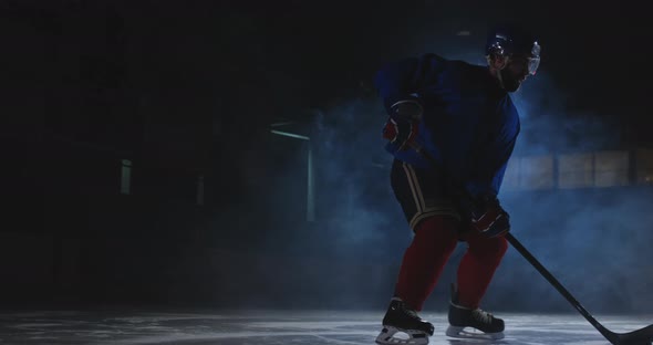 Man Hockey Player with a Puck on the Ice in Hockey Form Leaves with a Stick