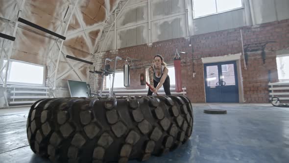 Woman Doing Sledgehammer Exercise with Tire