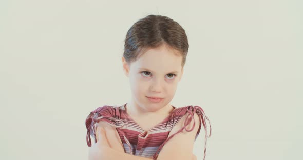 Little girl wearing a dress making funny faces on a white studio background