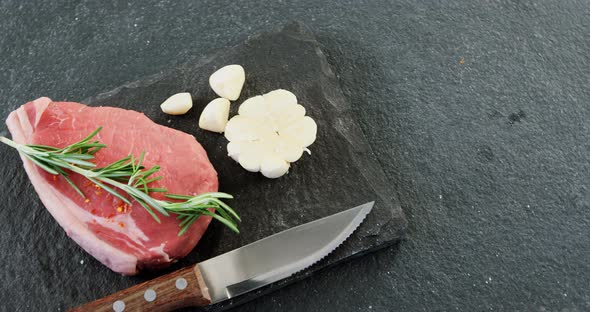 Sirloin chop, knife and garlic on chopping board