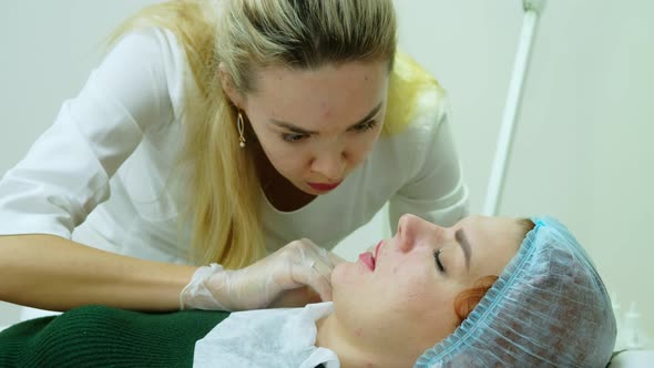 The Cosmetologist Makes Injections on the Client's Face in the Lip Area