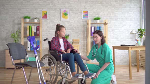 Doctor Examines the Leg of a Teenage Girl with a Disability in a Wheelchair