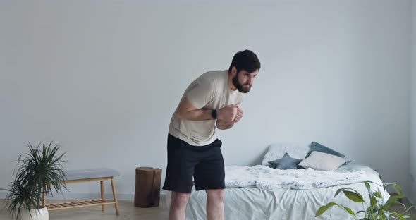 Millennial Guy Training at Home, Warming Up His Body
