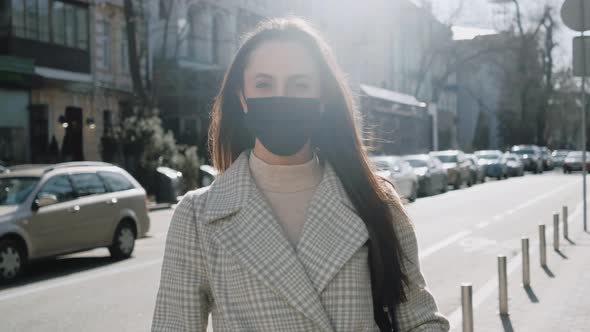 Portrait of a Young Woman with a Black Medical Mask Outdoors