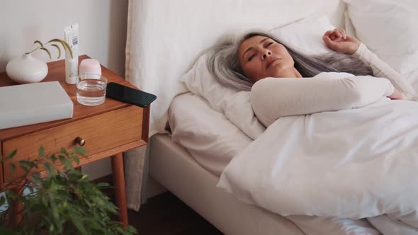 Smiling Asian woman wake up and looking at the phone