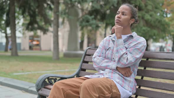 Pensive African Woman Thinking While Sitting Outdoor on Bench