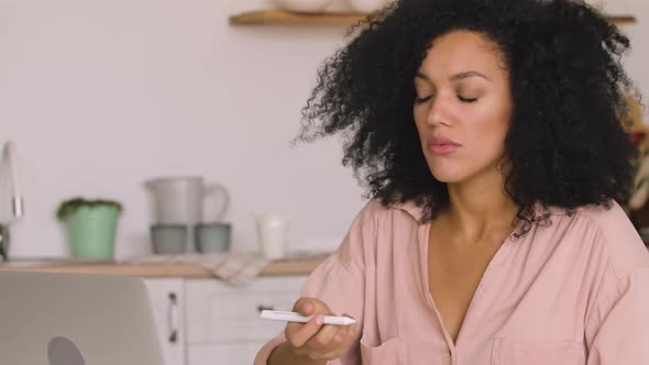 African American Woman Studying Online Remote Working Using Laptop While Taking Notes in Notebook