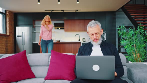 Caring Wife Calls Her Husband to Dinner While He Works While Sitting on the Couch with a Laptop