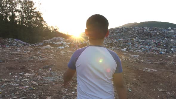 Boy Walking With Sunlight, Garbage At Background alt