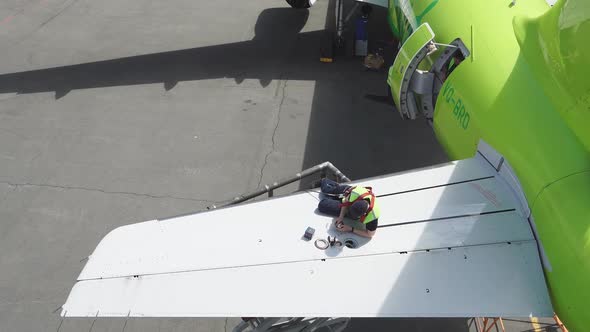 Passenger aircraft under repair. Engineer repairing wing of a passenger plane