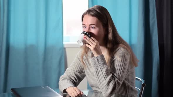 Young fair-haired woman is procrastinating by drinking coffee instead of working