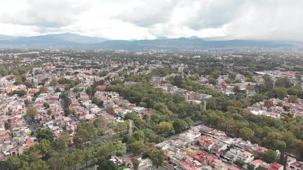 Drone view of a residential area in Mexico City, CDMX, with lots of houses on a cloudy day with blue