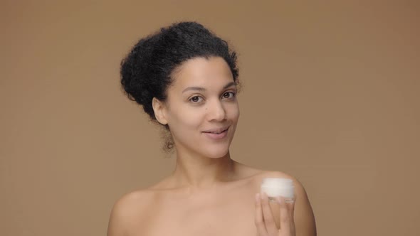 Beauty Portrait of Young African American Woman Smears Face Care Cream on Tip of Her Nose and Smiles