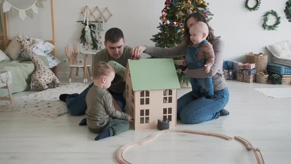 Young Parents Playing with Children By Xmas Tree