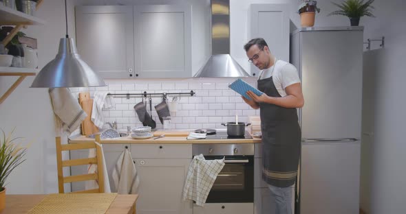 Young Man Reading Recipe on Tablet and Making Meal