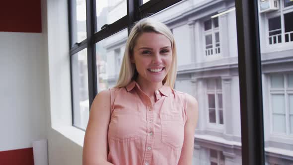 Caucasian businesswoman standing looking out of window in modern office