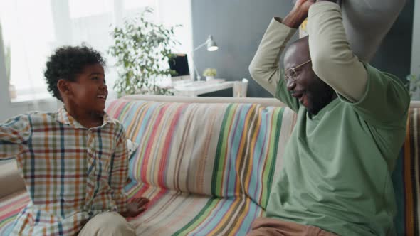 Afro-American Father and Son Having Pillow Fight on Sofa at Home