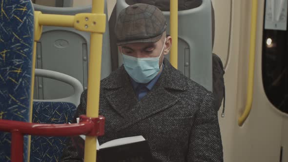 Young Handsome Man Sitting on Public Transport Reading a Book