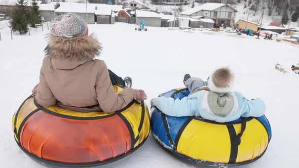 Young Girls Riding on Snow Tubes Down Hill