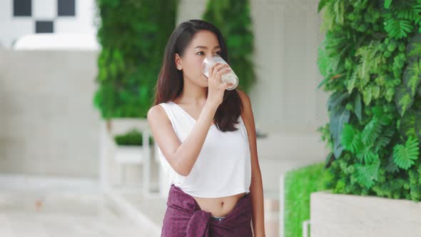 Attractive Asian woman drinking milk and smiling at home