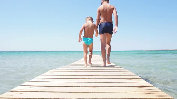 Children Boys Walk Along the Pier To the Sea the Pier Against the Background of the Azure Sea and