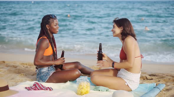 Best Girl Friends on Sandy Beach Sitting with Drinks