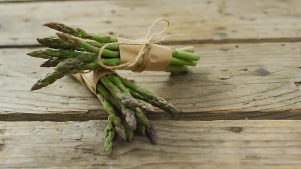 Video of two fresh asparagus bundles on wooden background