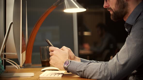 Overtime Work In Office. Handsome Businessman Working In Office And Talking On Smartphone.