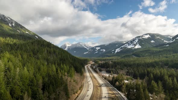 Traffic flows under boiling skies high up in the mountains of Washington, USA, aerial hyper lapse