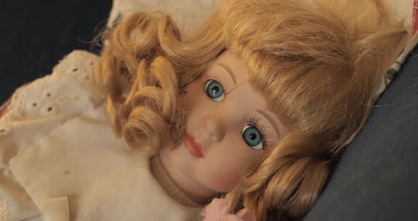 Slow push into a vintage porcelain doll with blonde curly hair and blue eyes