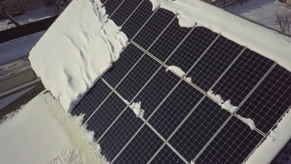 Closeup surface on a house roof covered with solar panels in winter with snow on top.