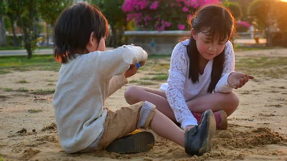 Asian Children Playing Sand In Playground Under Sunset