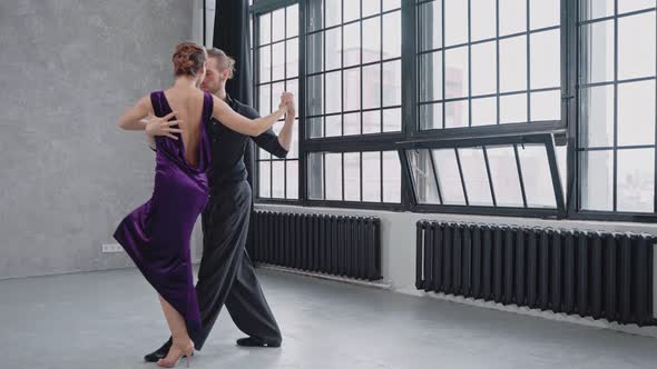 Shot of a Pair Sensually Dancing a Tango Against the Background of Large Windows