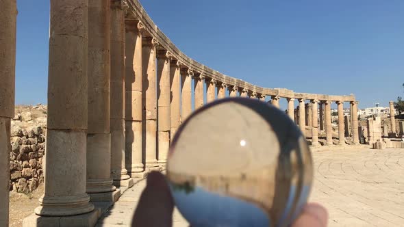 Crystal Ball Reflection Against Ancient Ruins of Roman City, Columns, Hand Holding